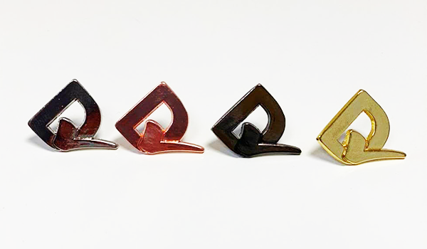 A photograph of four different coloured metal badges of the D tick logo.