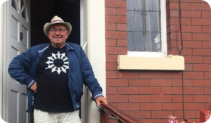 Photo of a smiling man outside a house.