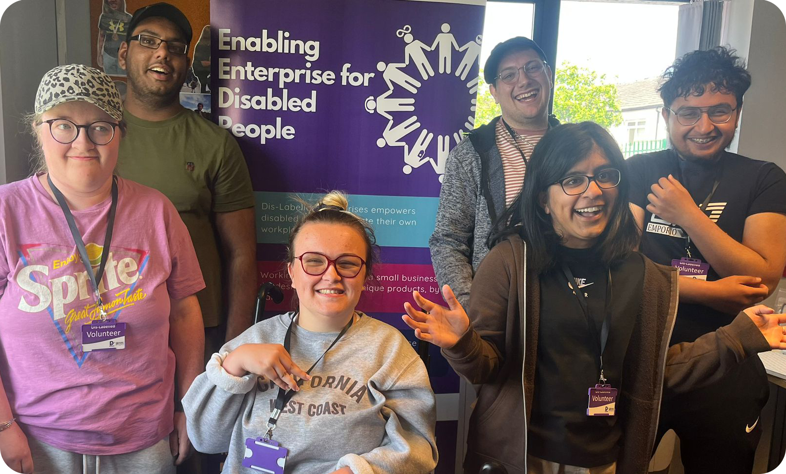 A group of young people smiling and laughing in front of a purple Dis-Labelled banner.